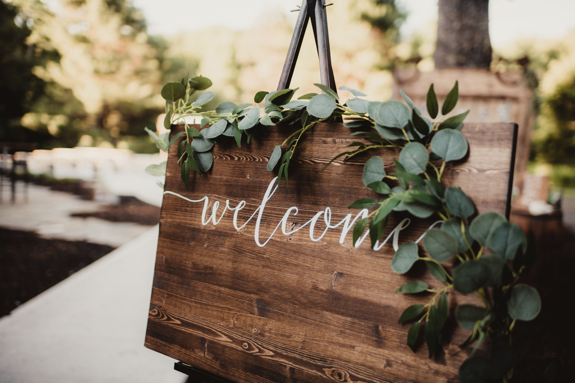Wood welcome sign with greenery set up at wedding ceremony